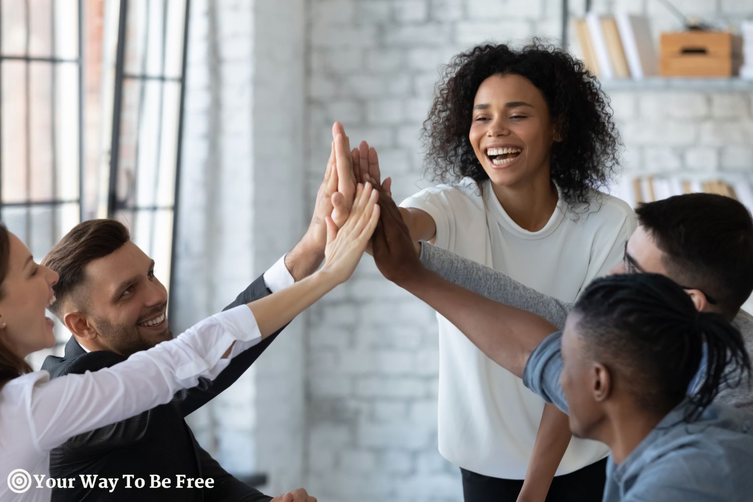 Overjoyed young multiracial businesspeople join hands give high five celebrate shared victory or win in office. Smiling millennial diverse employees engaged in teambuilding activity. Success, they are motivated