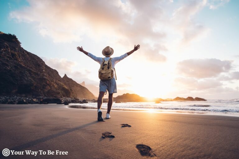 Young man arms outstretched by the sea at sunrise enjoying freedom and life, people travel wellbeing concept. He follows his dreams and passions living in the present moment to a passionate life